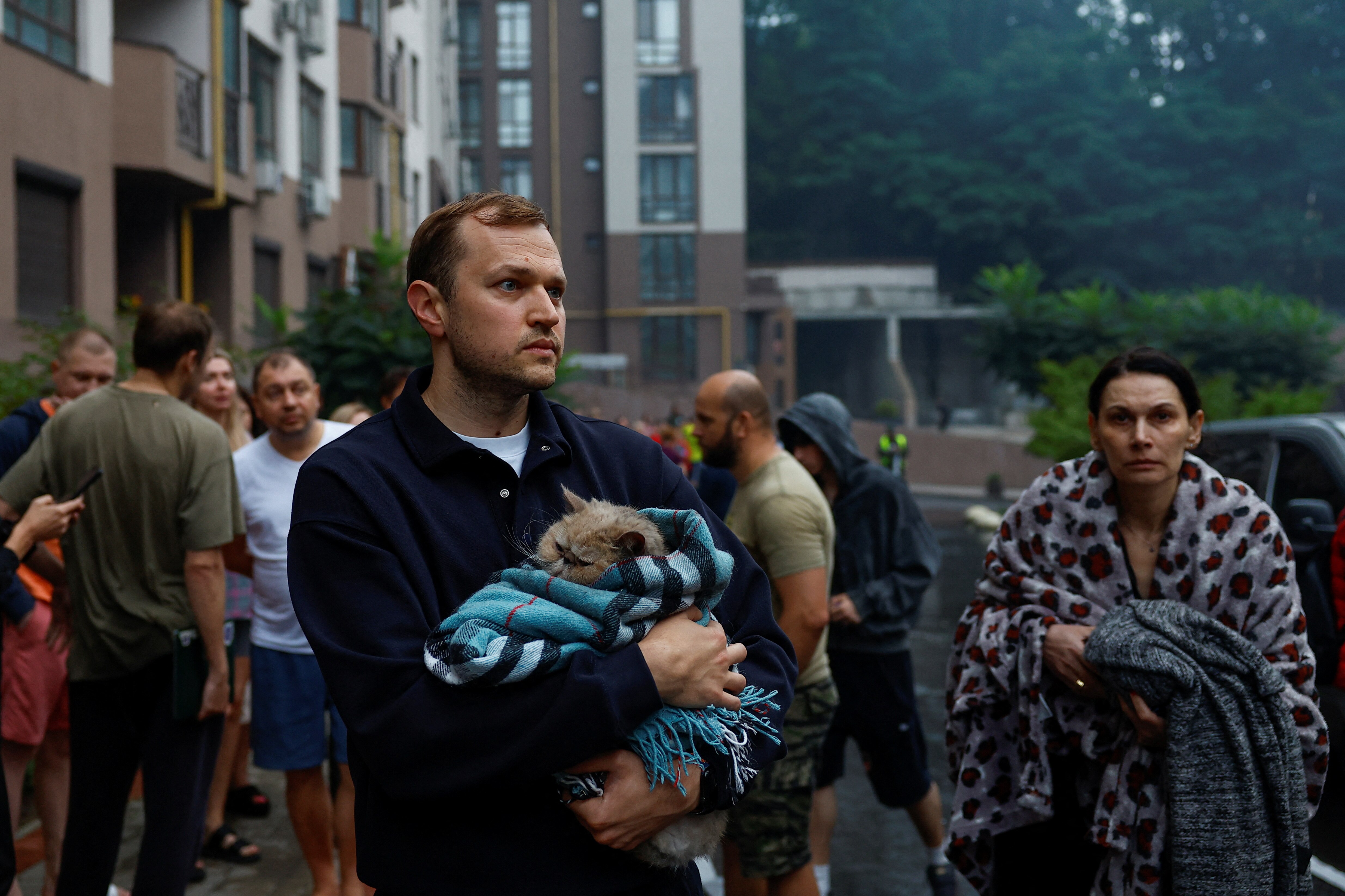Residents stand next to their apartment building hit by a Russian drone strike