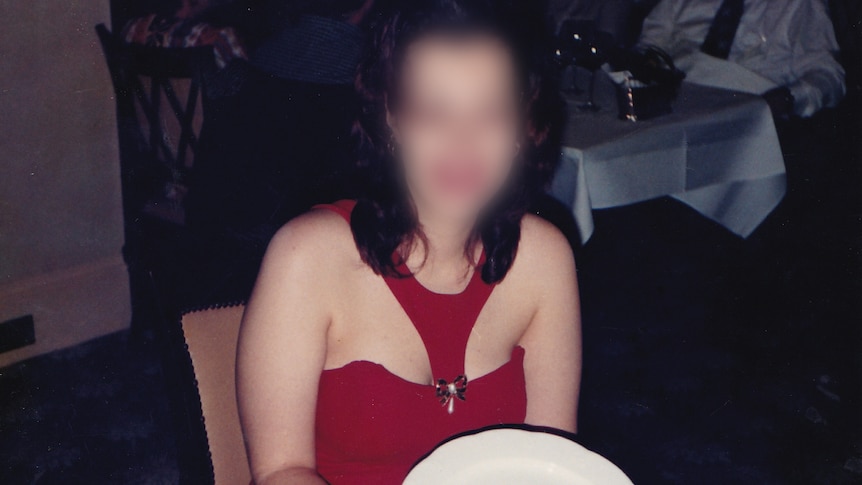 A woman, whose identity has been hidden, sits at a table holding a plate that says "Happy 21st Birthday".