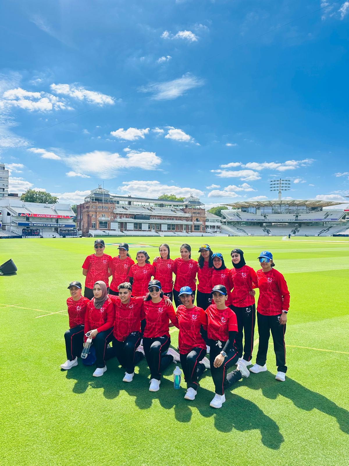 A group of cricket players stand on a large green field.