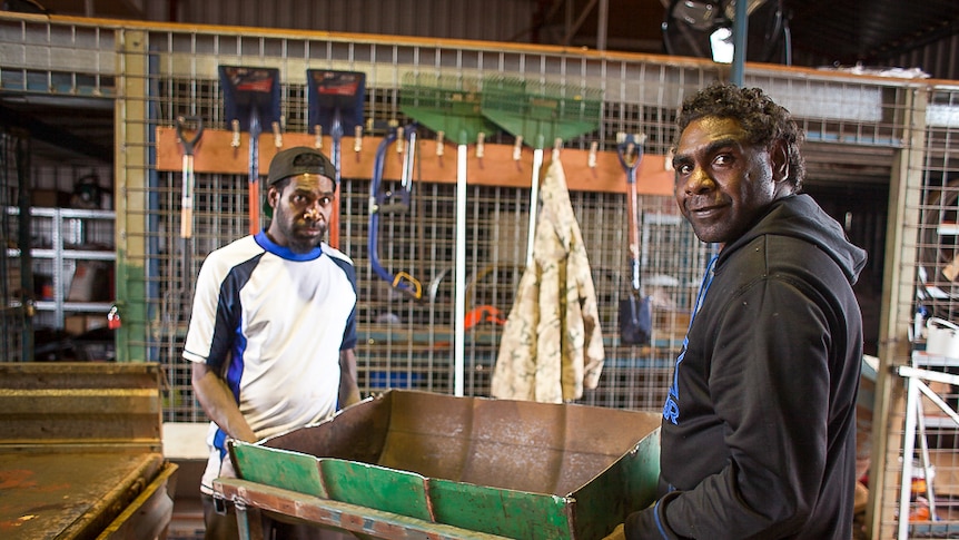 two men carrying a cut in half drum