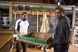 two men carrying a cut in half drum