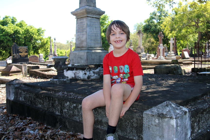 Jack Chenoweth, 7, sits in the South Brisbane Cemetery.