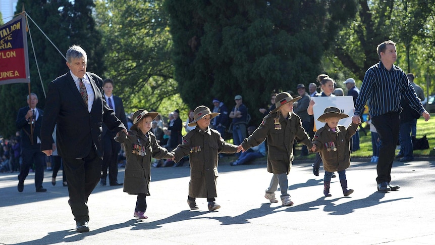 A family marches towards the Shrine of Remembrance during the Anzac Day march in Melbourne.