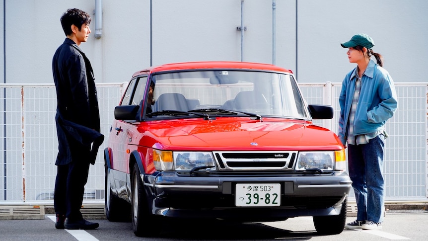 a man and a woman on either side of a bright red, highly polished SAAB looking at each other.