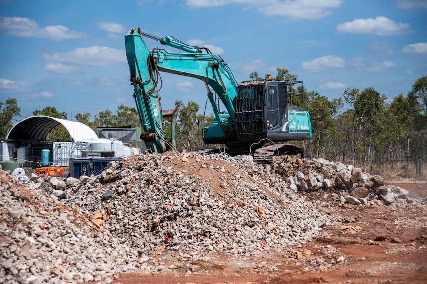 A digger operates on top of a mound of smashed up concrete.