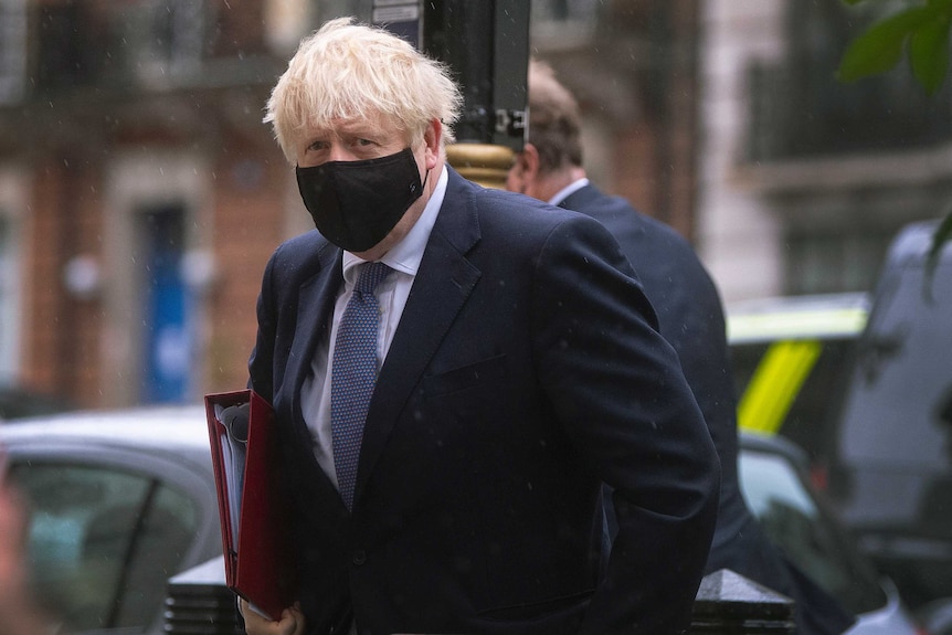 Boris Johnson wearing a black mask outdoors