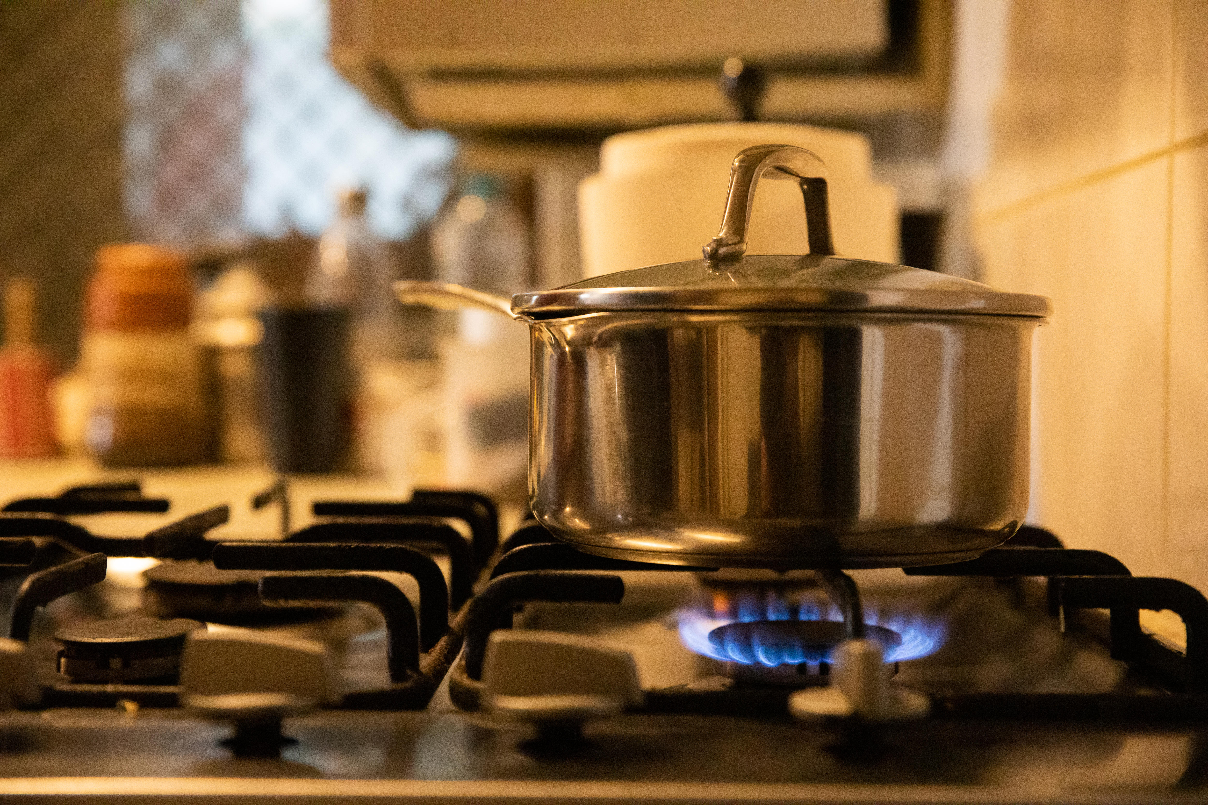 A pot boils on a gas stove in a residential kitchen