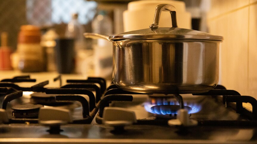 A pot boils on a gas stove in a residential kitchen