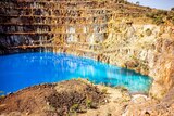 A picture of an old mine pit, showing each level of the mine, with bright blue and green water at the base.