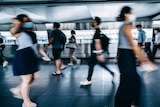 A blurred image of commuters in face masks walking during rush hour.