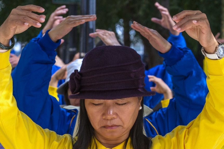 Woman in yellow hold hands above her head, meditating.