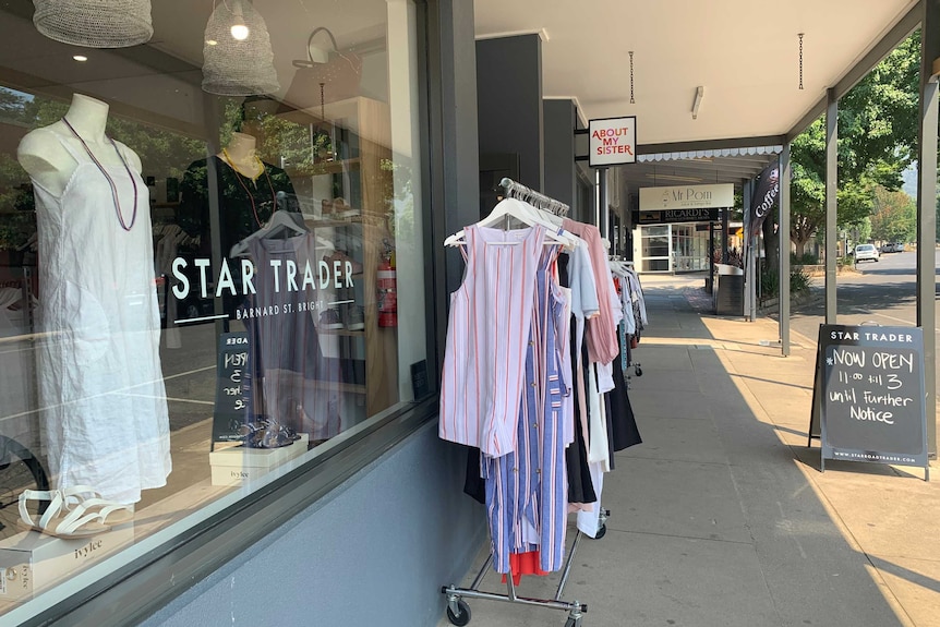 A shop with clothing for sale outside in an otherwise empty-looking country town.