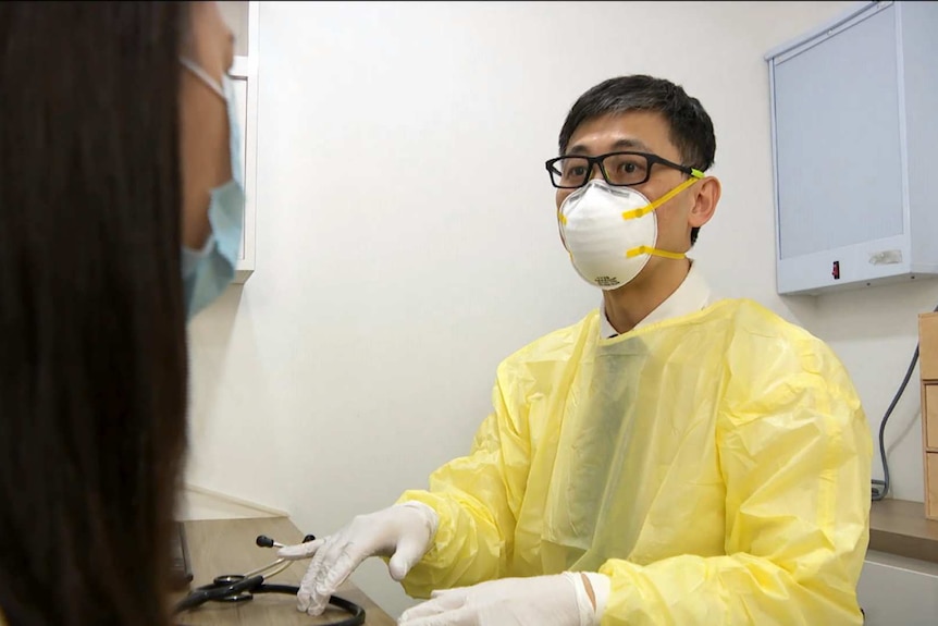 A health worker in a mask speaks with a patient.