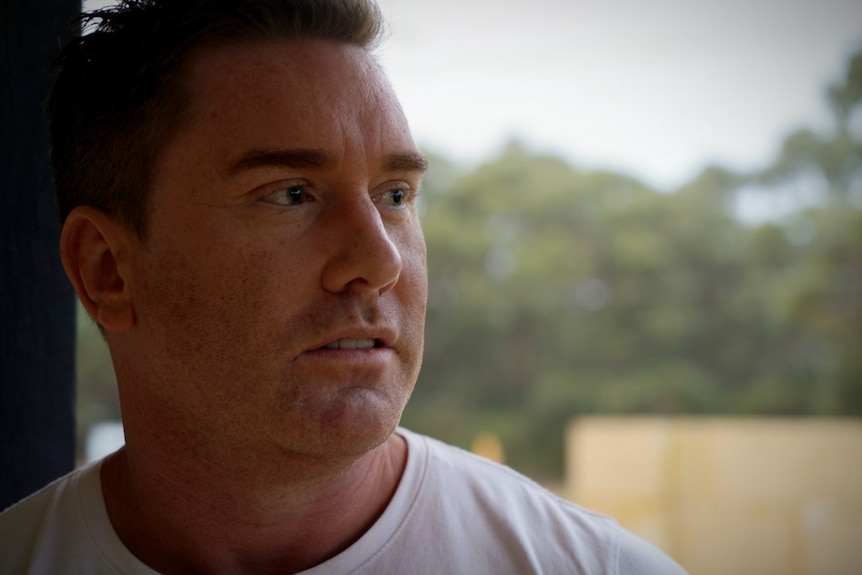 A close up of man leaning against a door.