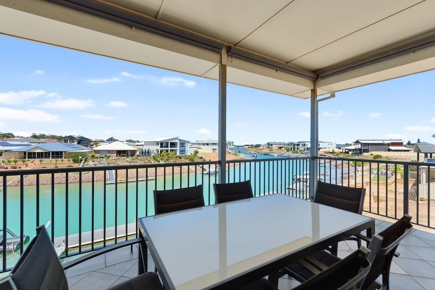 A second-storey verandah overlooks a body of water and other houses.