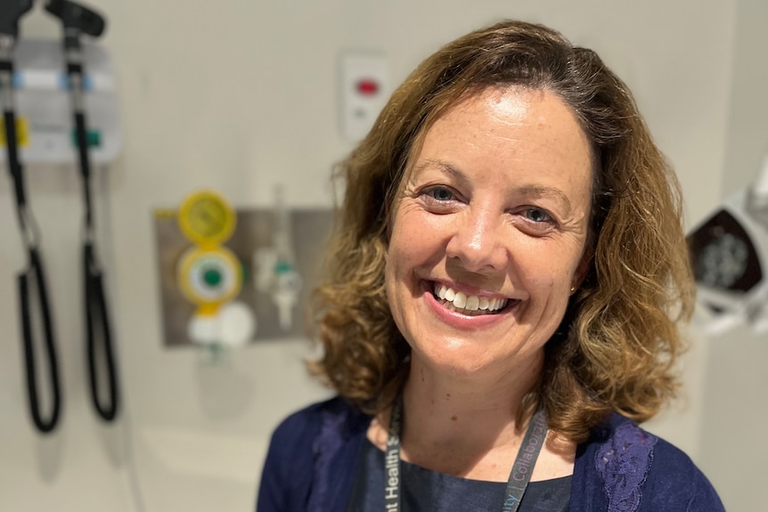 Woman sitting in a hospital office, smiling.