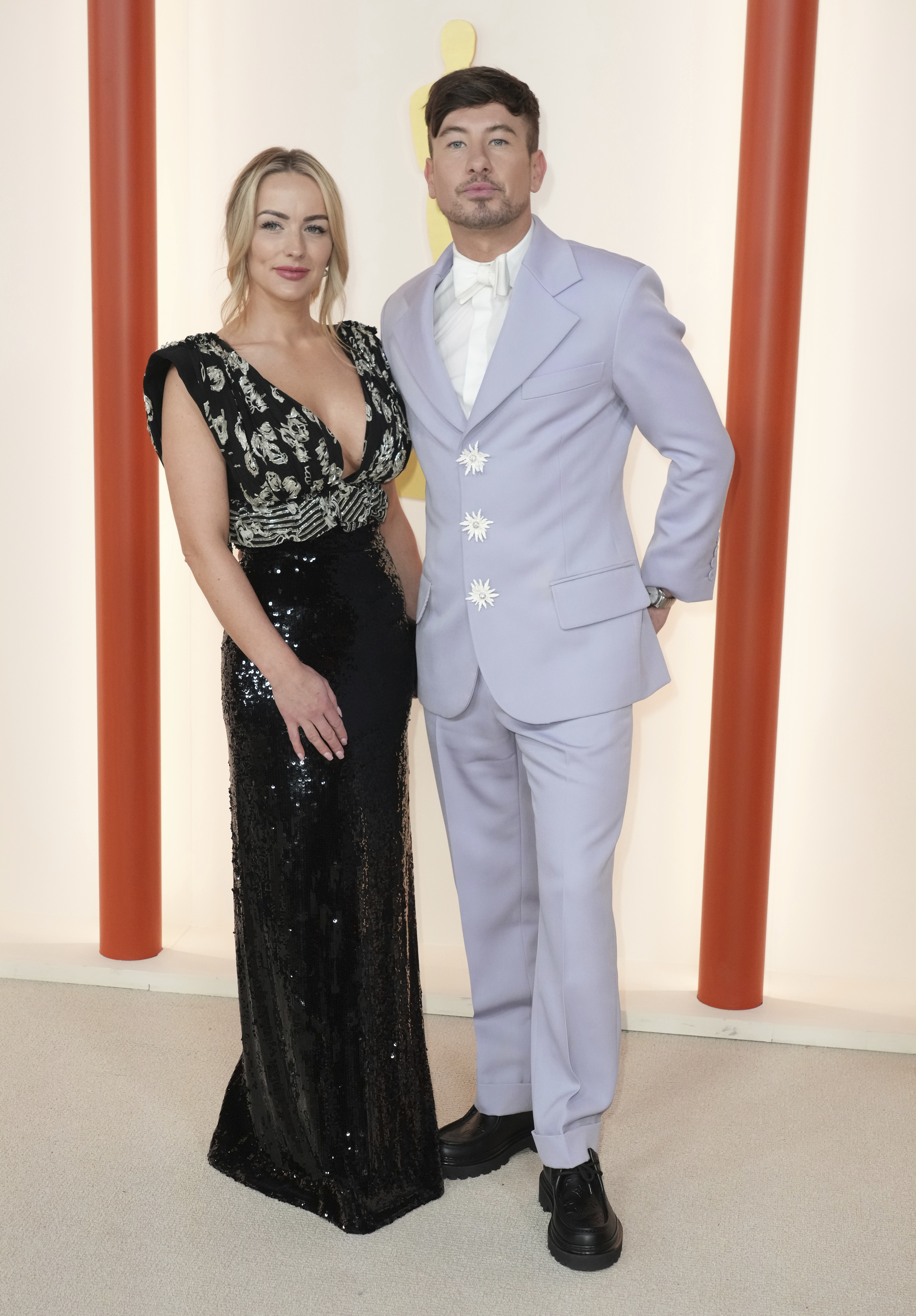 Alyson Sandro in a long black sparkly gown and Barry Keoghan wearing a pastel purple suit with white starburst buttons