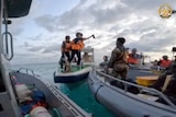 Chinese Coast Guards hold an axe as they approach Philippine troops on boats. 