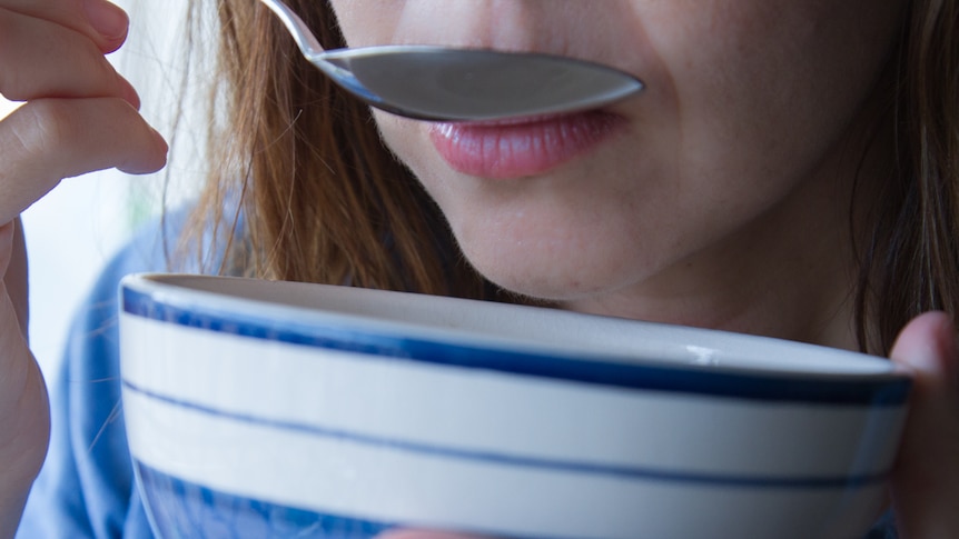 A woman eats from a bowl.