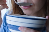 A woman eats from a bowl.
