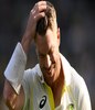 澳大利亚击球手大卫华纳在 Gabba 带着头盔离开球场时用手抚摸着头发。