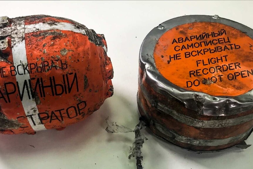 Two damaged flight recorders of a Russian passenger plane that crashed. They are mostly fluoro orange.