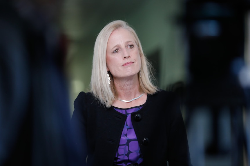 Katy Gallagher wearing a black jacket and purple top, looking to the right 