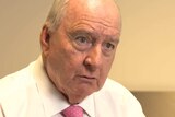 Alan Jones wears a white shirt and red tie