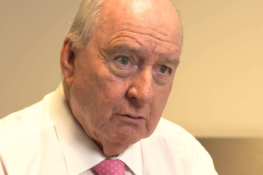 Alan Jones wears a white shirt and red tie