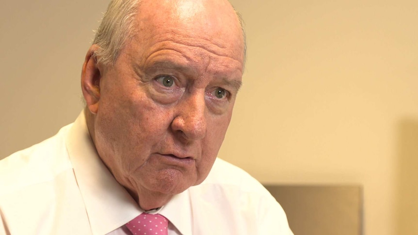 Alan Jones wears a white shirt and red tie