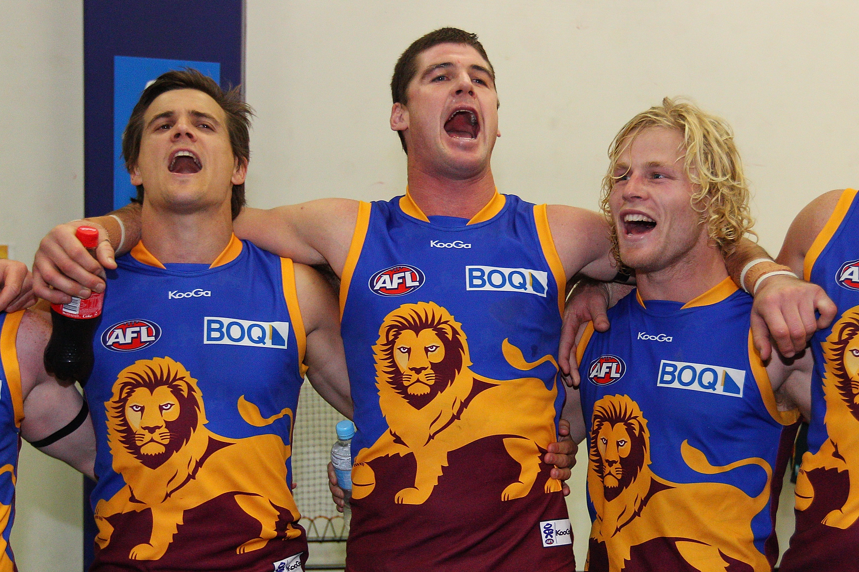 Three Brisbane players sing song together arm in arm