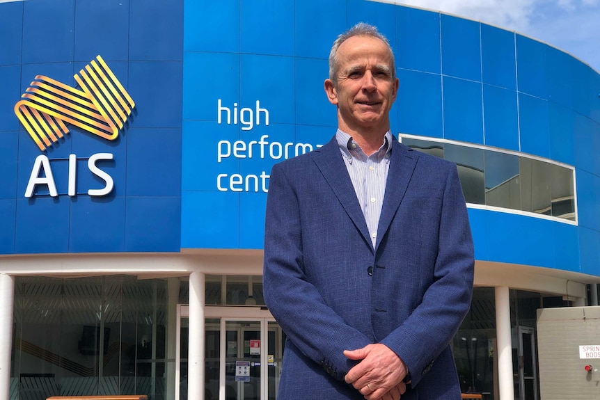 A man wearing a blue blazer and business shirt standing outside the AIS building