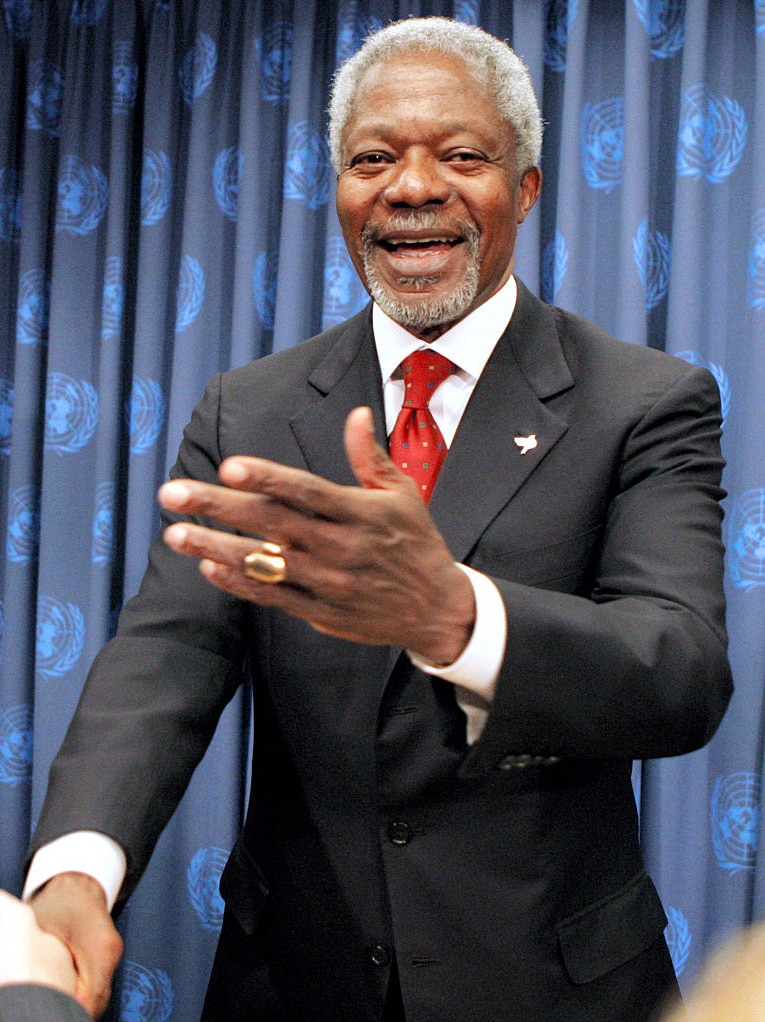 Kofi Annan smiles and shakes a hand