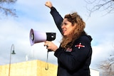 Diana Asmar speaks through a megaphone with her fist in the air