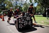 teenagers wearing helmets race a couch on the street