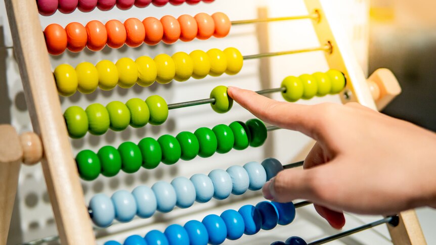 A finger points to an abacus