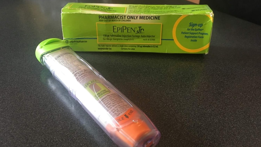 An EpiPen sits on a bench near its packaging.