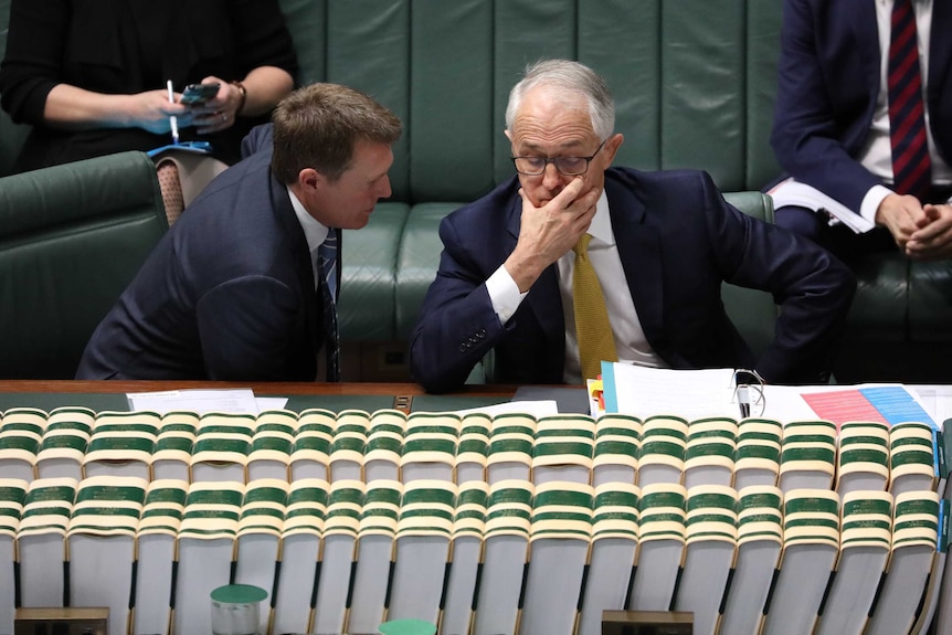 Porter leaning towards Turnbull. Turnbull hand on face, looking downwards.