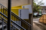 A bunch of yellow rental signs leaning up against a wall and staircase at the back of a building