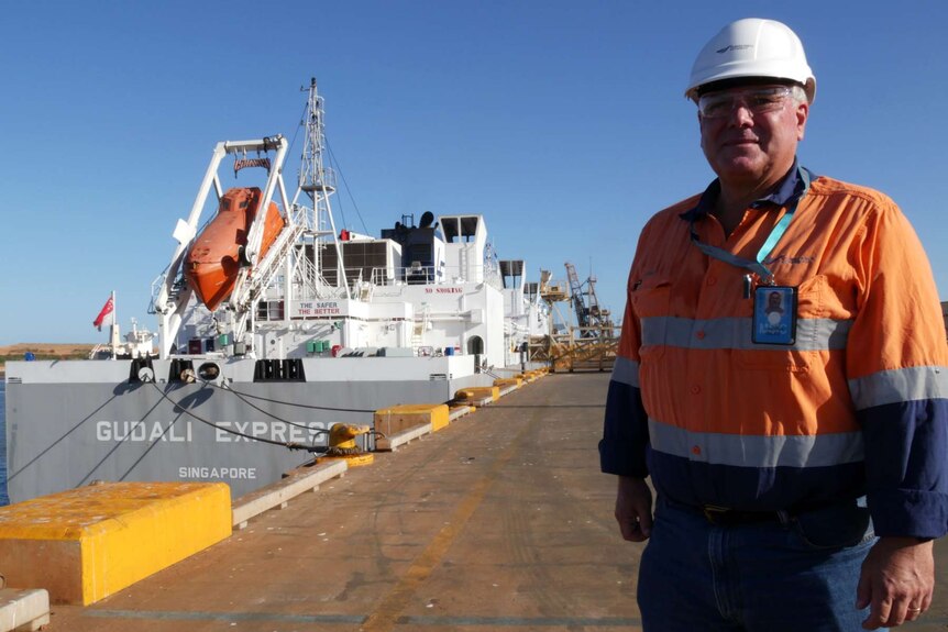 Man standing in front of ship docked in port