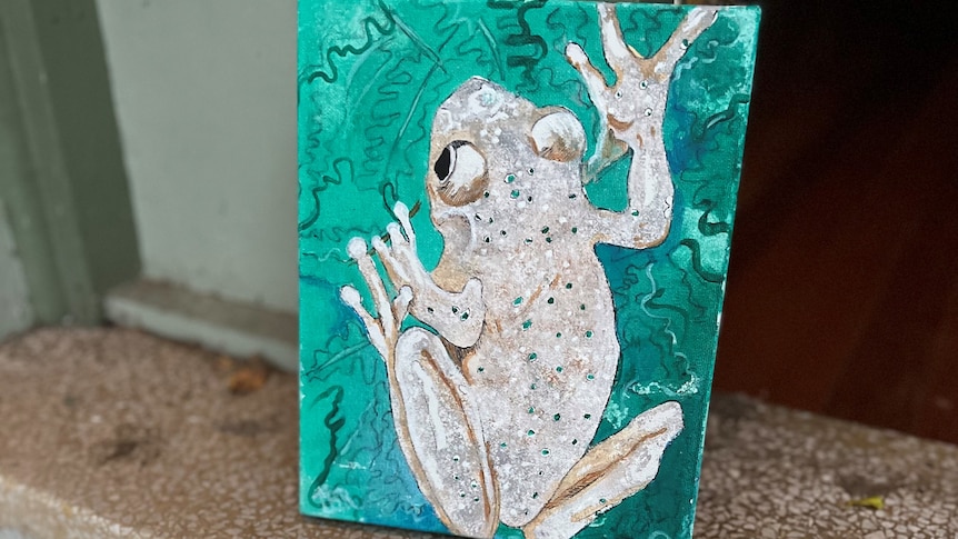 painting of a green frog on a small canvas on a doorstep