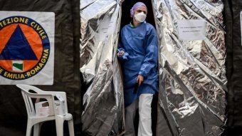A doctor walks out of a silver tent in Italy.