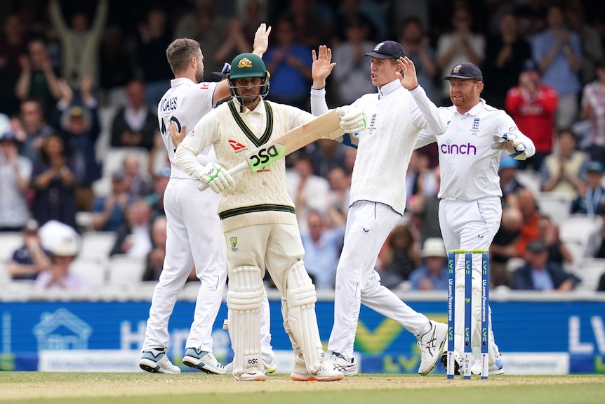 Usman Khawaja stands at the crease as England players celebrate behind him