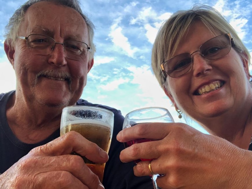 A man and woman smile at the camera as the toast with glasses of champagne.