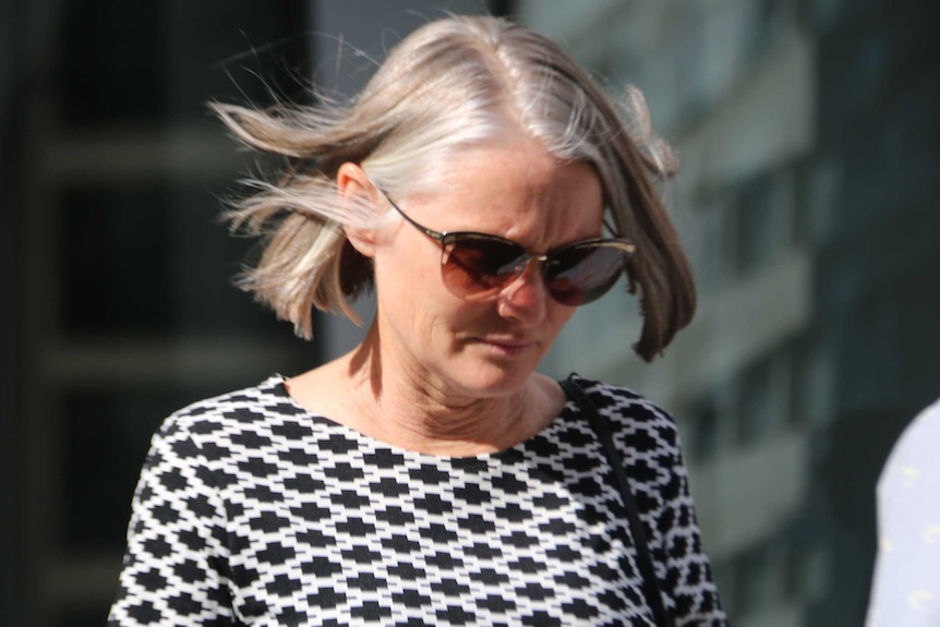 A woman in a black and white dress outside court.