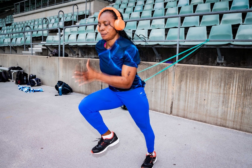 Isoken Igbinosun runs with a band tied around her waist and attached to a metal bar.