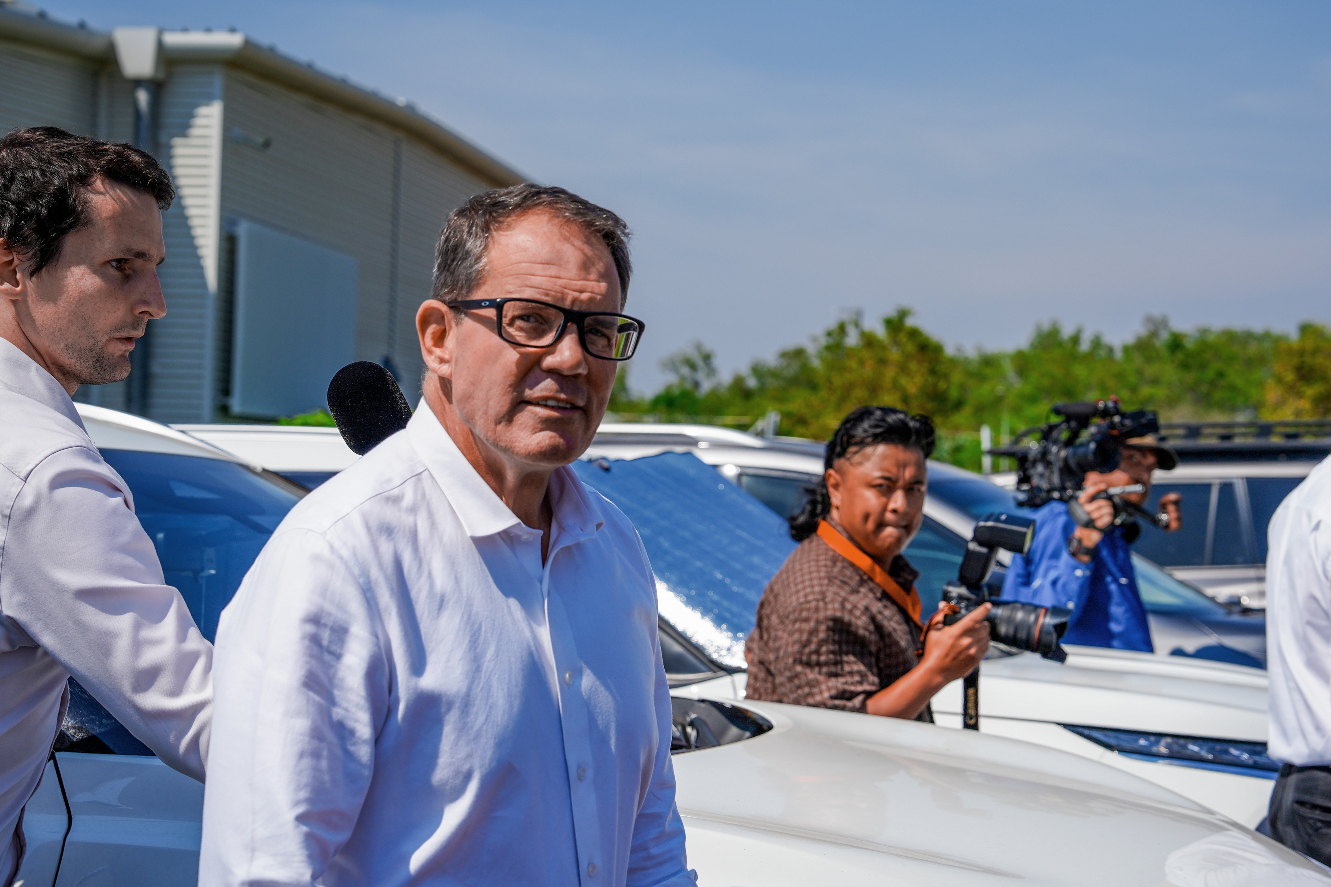 Solomon MP Luke Gosling walking through a car park, surrounded by media