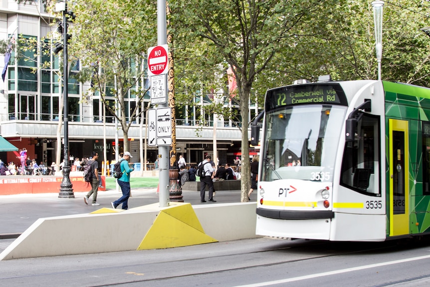 A tram stop on a city street. Yellow geometric shapes form part of stop.