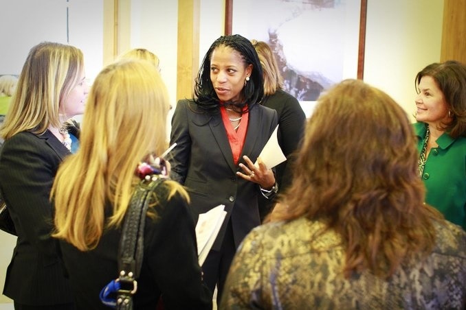 A black woman talks to a group of white women