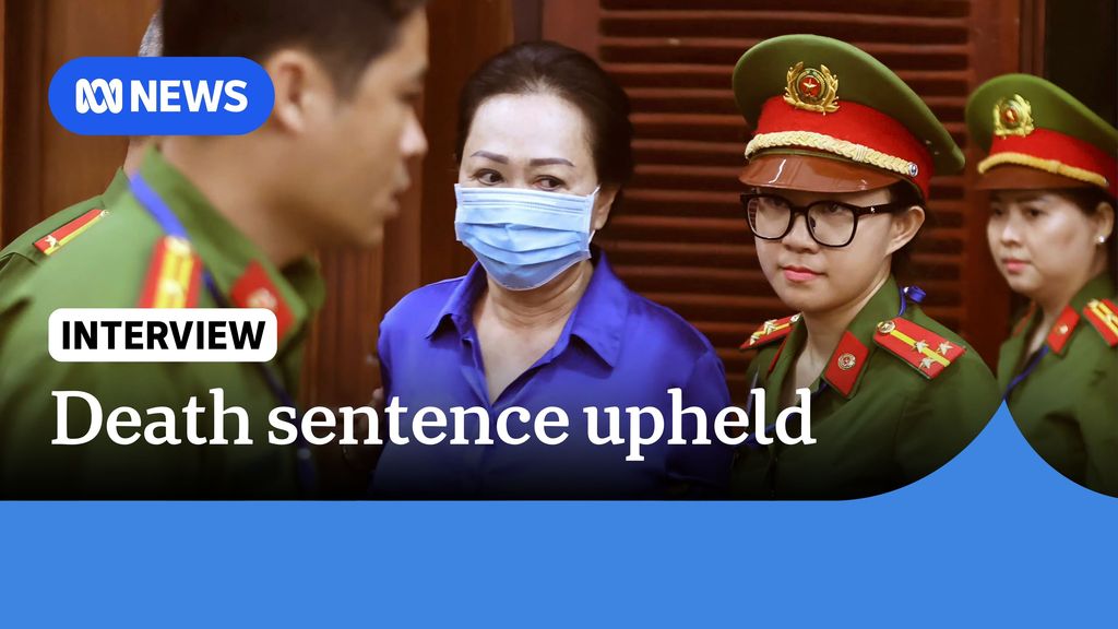 Death sentence upheld: A woman in a blue surgical facemask escorted by troops in khaki military uniform.